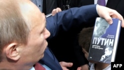 Владимир Путин держит в руках книгу о себе. Пенза, 9 марта 2011 года.