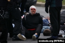 Belarusian police stand over a man with a heavily bandaged head after security forces forcibly broke up an anti-government protest in Minsk and detained hundreds of people on October 11.