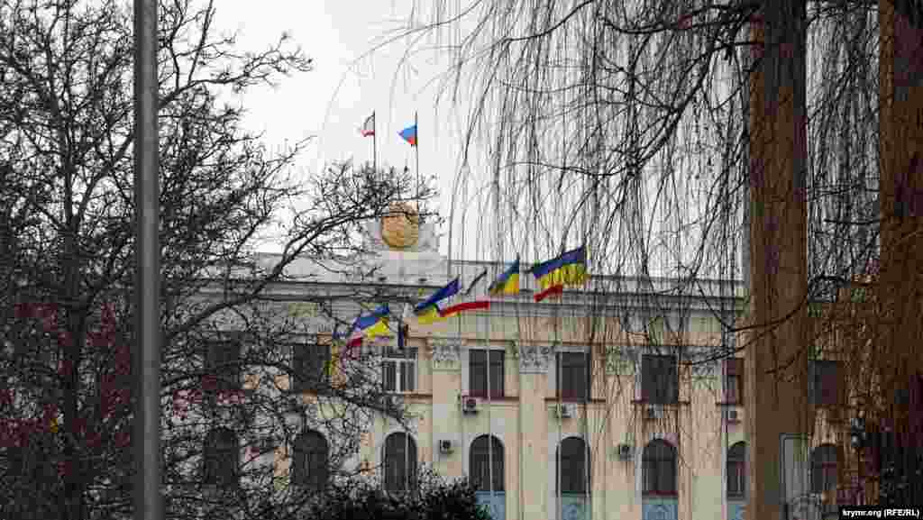 Последние украинские флаги в городе. «Ополченцы» бы их давно сорвали, но флагштоки стоят перед зданием Совета министров, в зоне оцепления, куда не пускает милиция. А «зеленые человечки» пока из Совмина и Верховной Рады так и не выглянули. В этот день, в пятницу, администрация школ в центре Симферополя рекомендовала школьникам пропустить занятия. Не приказала, а именно рекомендовала Это был последний день зимы 2014 года.