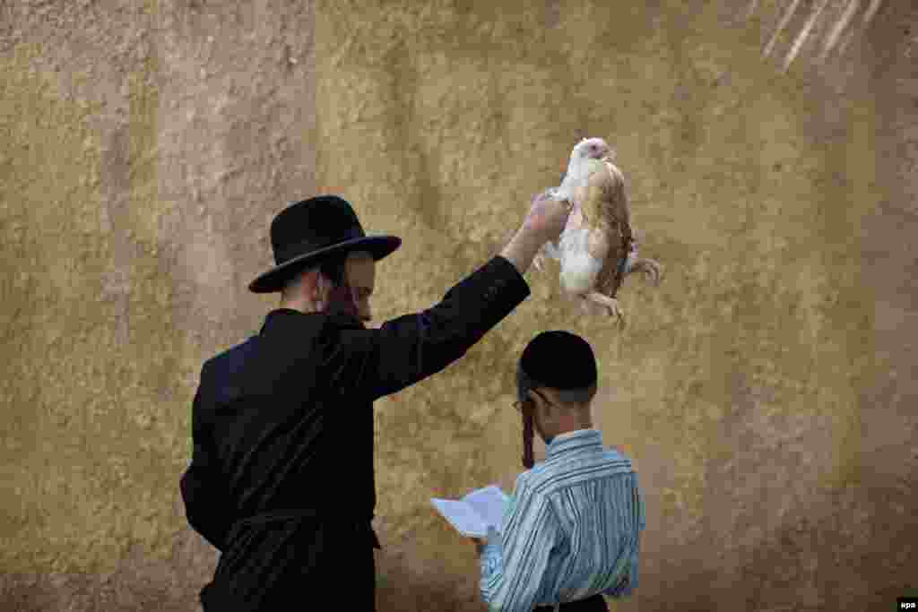 An ultra-Orthodox man performs the Kaparot&nbsp;ritual in Jerusalem. The Kaparot is a blessing and prayer recited as a live fowl -- often a&nbsp;chicken -- is passed over a person&#39;s head, symbolically transferring that person&#39;s sins into the bird, which is then butchered and eaten or donated to charity. (epa/Abir Sultan) 