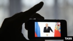 Russia -- A man watches a live TV broadcast of Russian President Vladimir Putin's address on his smartphone, in Ivanovo, December 3, 2015