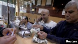 Iran -- A currency exchange dealer counts US dollar banknotes at his shop in a shopping centre in northern Tehran, January 17, 2016