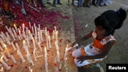 A girl lights a candle during a candlelight vigil for the victims of garment-factory fire in Karachi that killed at least 258 people.
