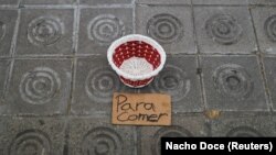 „Pentru mâncare” - inscripție sub coșul unei persoane fără adăpost, pe un trotuar la Barcelona, 4 mai 2020