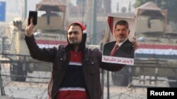 Сторонник свергнутого президента Египта Мохаммеда Мурси держит в руках портрет Мурси и Коран. Каир, 25 января 2015 года.