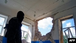 В Славянске вооруженный пророссийский активист показывает журналистам повреждения, якобы нанесенные жилому дому в результате обстрела со стороны украинской армии