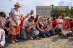 Людзі сталі на калені, каб ушанаваць памяць загінулых падчас пратэстаў.