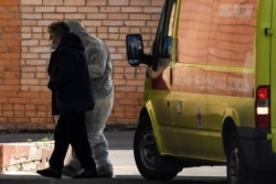 Мәскеудегі ауруханалардың бірінде қорғаныш киім киген медициналық қызметкер науқасты ішке апара жатыр. 3 мамыр 2020 жыл.