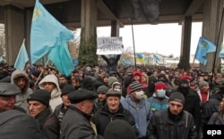 Activists hold up Crimean Tatar flags and a banner reading "Crimea = Ukraine!" during a protest near the parliament building in Simferopol, Crimea, in February 2014.