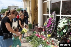 Люди возлагают цветы у оружейного магазина в день похорон погибшего от рук предполагаемых исламистов продавца Андрея Максименко. Актобе, 8 июня 2016 года.