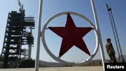 A North Korean soldier stands guard in front of the rocket on a launch pad northwest of Pyongyang.