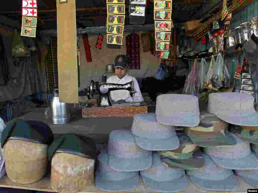 A boy sews military uniforms at a market in Kabul.