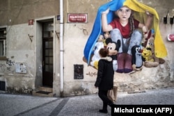 Мурал, що зображує дитину, яка ховається від війни під прапором України, створений вуличним художником ChemiS. Прага, Чехія, 19 березня 2022 року