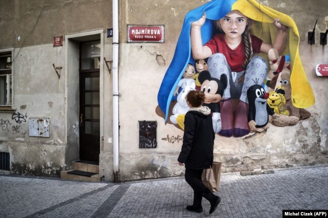 Мурал, що зображує дитину, яка ховається від війни під прапором України, створений вуличним художником ChemiS. Прага, Чехія, 19 березня 2022 року