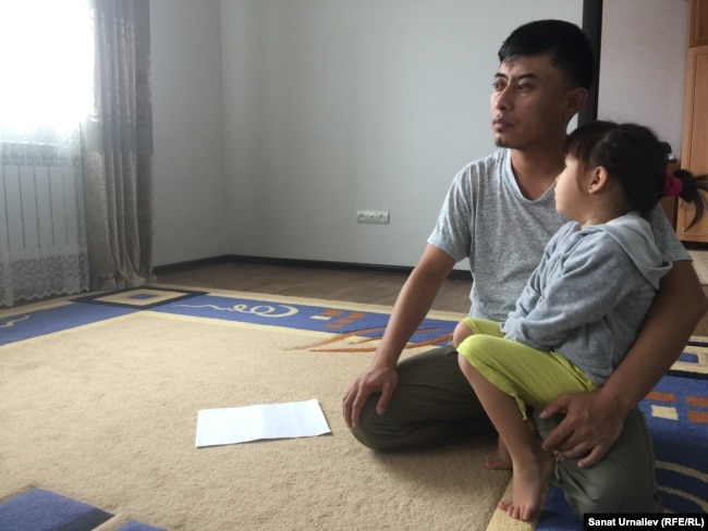 Berikbek Samat, a school teacher from Chapaev, with one of his daughters, whose older sister is currently not attending school because she can't wear a head scarf to classes.