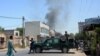 Afghan security personnel secure a road as smoke billows from the site of a suicide attack in Jalalabad on July 31.