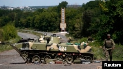 Украина сарбазы істен шыққан танкінің қасынан өтіп барады. Славянск, 5 шілде 2014 жыл.
