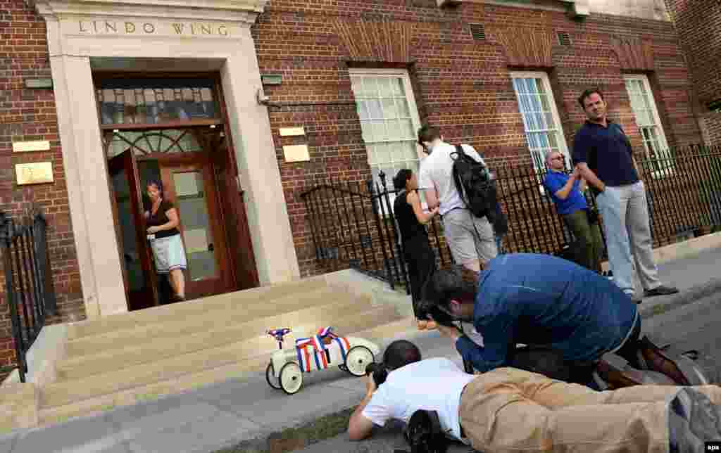 Photographers take pictures of a toy car, chosen as a present to the royal family by users of a French baby-gift website.