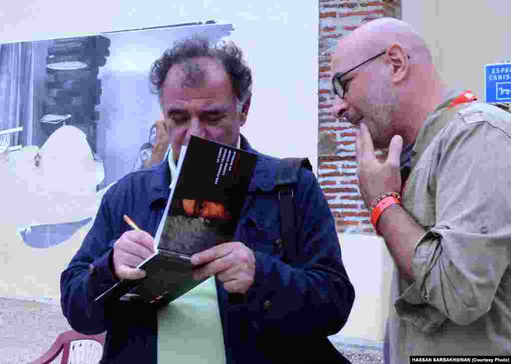 آلفرد یعقوب&zwnj;زاده، عکاس ایرانی مقیم پاریس، در حال امضای کتاب عکس&zwnj;های نمایشگاه خود