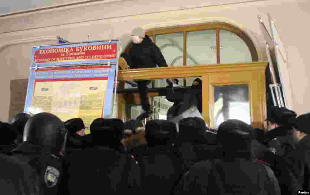 Anti-government protesters get inside the regional administration headquarters as they attempt to take over during a rally, with Interior Ministry members standing guard in the foreground, in the town of Chernivtsi in southwestern Ukraine, January 24.