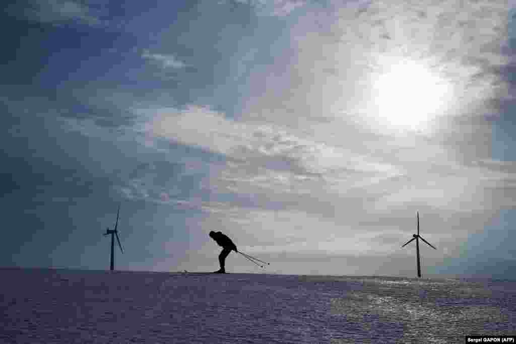 A man skis down a slope in front of wind turbines outside the Belarusian village of Kreva, some 100 kilometers northwest of Minsk. (AFP/Sergei Gapon)