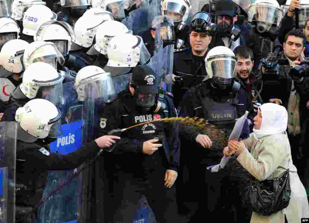 Turkey -- A woman (R) confronts riot policemen as they spray tear gas on demonstrators trying to march, in Istanbul, January 9, 2014