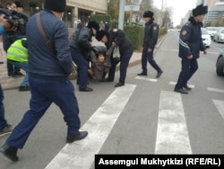 Police in Nur-Sultan detain a woman who was trying to gather for an anti-government demonstration.
