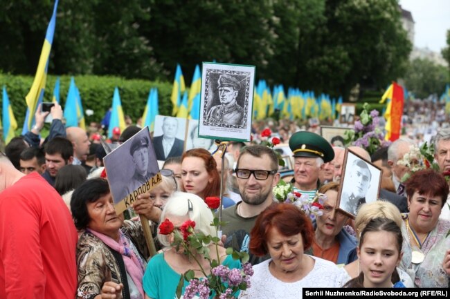 Чоловік із портретом головного командира УПА Романа Шухевича вирішив також пройтися разом із учасниками акції «Безсмертний полк». На нього не звертали уваги, допоки він не почав вигукувати гасло «Слава Україні!». Київ, 9 травня 2018 року