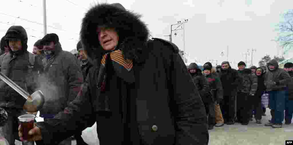 Homeless people line up for free hot food at a kiosk organized by social services in Kyiv.