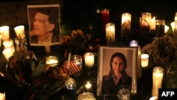 Candles surround portraits of federal judge John Roll, who was killed in the attack, and Arizona Representative Gabrielle Giffords, who were shot in the Tuscon, Arizona, rampage.