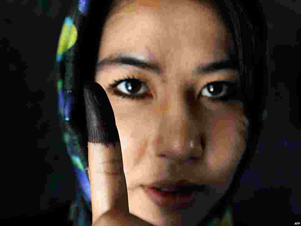 Молода афганська жінка показує палець, помічений чорнилом, після того, як вона проголосувала на президентських виборах 20 серпня в Кабулі
