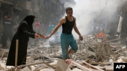 Syria -- People walk amid the rubble of destroyed buildings following a reported air strike on the rebel-held neighbourhood of al-Kalasa in the northern city of Aleppo, April 28, 2016