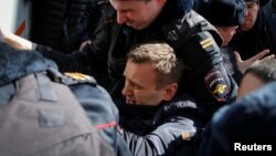 Полицейские затаскивают Алексея Навального в автозак