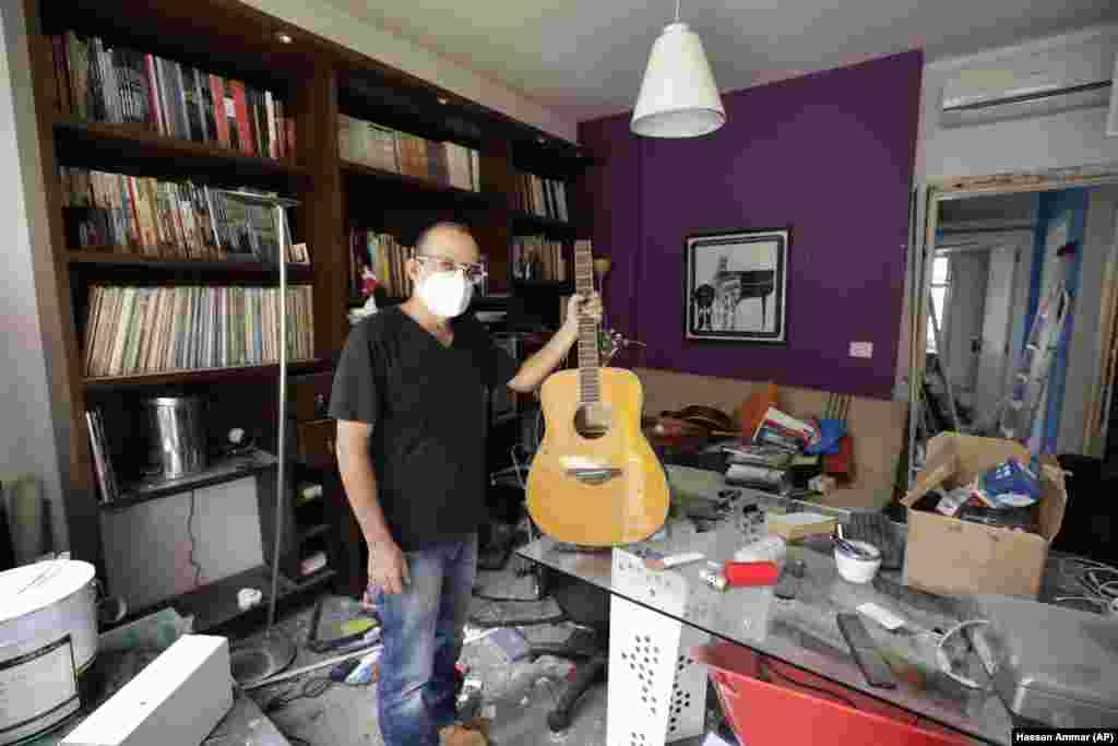 Alain Shoucair, 38, poses for a photograph as he holds his broken guitar at his destroyed apartment after Tuesday's explosion in the seaport of Beirut, Lebanon, Thursday, Aug. 6, 2020.