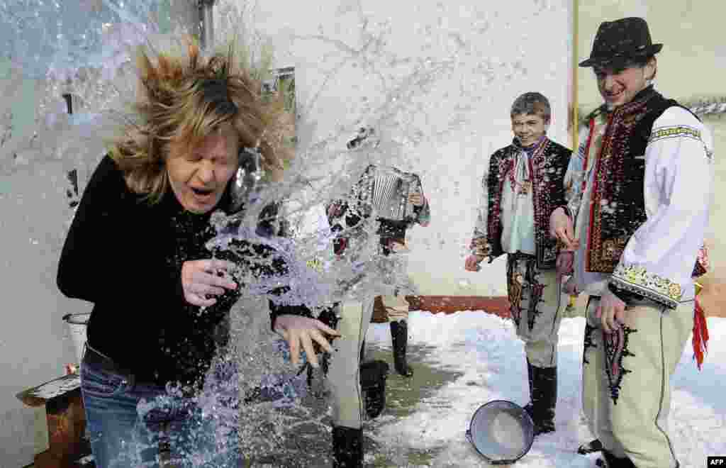 Young Slovak men dressed in traditional costumes pour a bucket of cold water over a woman as part of Easter celebrations in the village of Trencianska Tepla, 145 kilometers north of Bratislava. Slovakia&#39;s men traditionally splash women with water and hit them with a willow to evoke youth, strength, and beauty for the upcoming spring season. (AFP/Samuel Kubani)