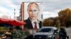 RUSSIA -- An elderly woman walks around a street market, with a graffiti depicting Russian President Vladimir Putin on the wall of a house seen in the background, in the town of Kashira, outside Moscow, October 10, 2017