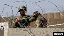 An Afghan soldier keeps watch at the gate of a British-run military training academy Camp Qargha, in Kabul August 5, 2014.