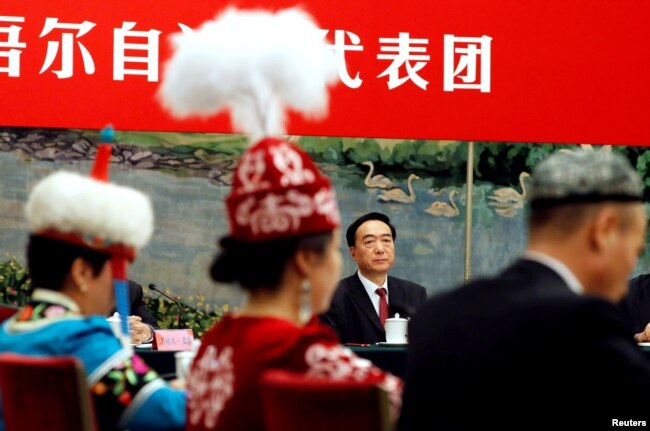 Şınjañ-Wyğwr avtonomiyalıq audanınıñ partiyalık jetekşisi Çen' Cyuan'go (ortada) Kompartiya qwrıltayında. Pekin, 19 qazan 2017 jıl.