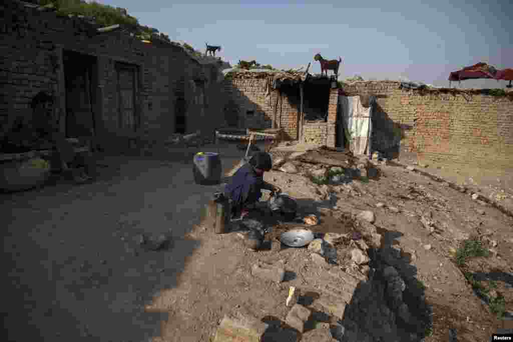 Samiullah, who says he is 14 years old, washes dishes outside the mine.