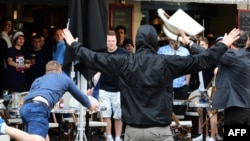 A Russian football supporter lobs a chair toward England fans sitting in a cafe at the 2016 European soccer championship in France. 