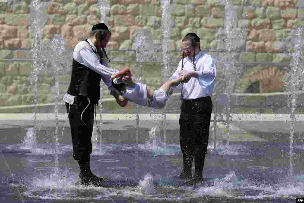 Ultraorthodox Jews cool themselves in a water fountain in Jerusalem next to the Old City walls on July 23 2013.&nbsp;