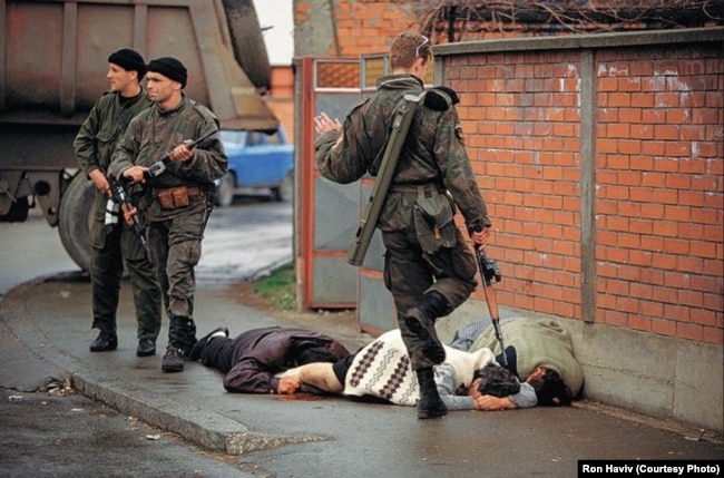 Снимка на американския фоторепортер Рон Хавив, която се смята за емблематична за войната. Тримата мъже са от сръбската паравоенна организация на Аркан "Тигрите". Един от тях рита вече убита жена в босненския град Биелина на 2 април 1992 г. Смята се, че войната е започнала ден по-рано.