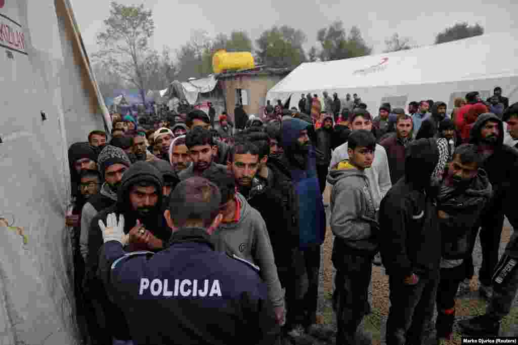 A Bosnian policeman in the Vucjak camp talks with migrants. Bosnia has seen a buildup of Middle Eastern and Asian migrant numbers since nearby EU members Hungary, Slovenia, and Croatia sealed their borders to undocumented migrants.