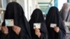 Burqa-clad women show ID cards as they wait to cast their votes in Kandahar. Is their willingness to participate a sign of Taliban weakness?