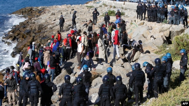 Мигранты в окружении итальянских полицейских на берегу Средиземного моря на французско-итальянской границе. Вентимилья, 30 сентября 2022 года