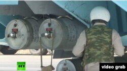 A screen-grab from a news segment aired by RT, which showed two canister-like attachments under the wing of a Russian jet that have been identified by independent activists as cluster munitions.