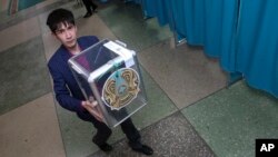 Сотрудник избирательной комиссии несет урну для подсчета бюллетеней на избирательном участке во время президентских выборов в Нур-Султане, столице Казахстана, в воскресенье, 9 июня 2019 года.