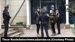Полиция қызметкерлері белсенділер Әсия Төлесова мен Бейбарыс Толымбековты әкімшілік сотқа жеткізген сәт. Алматы, 21 сәуір 2019 жыл.