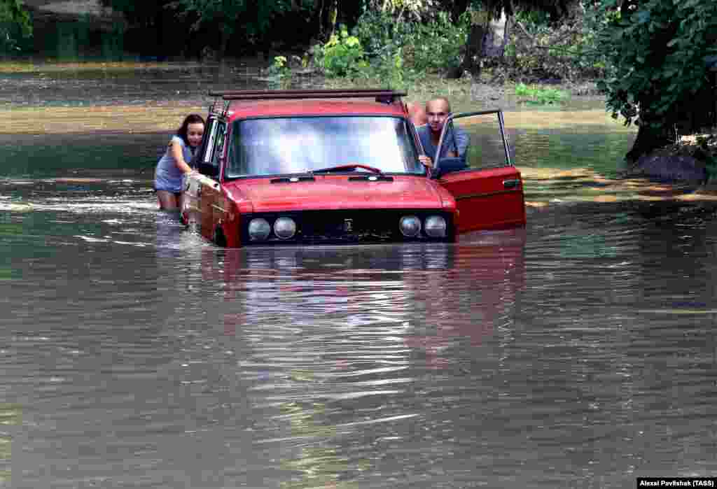 People push a car in a street flooded after a heavy downpour in the Crimean city of Yevpatoriya. (TAS/Aleksei Pavlishak)