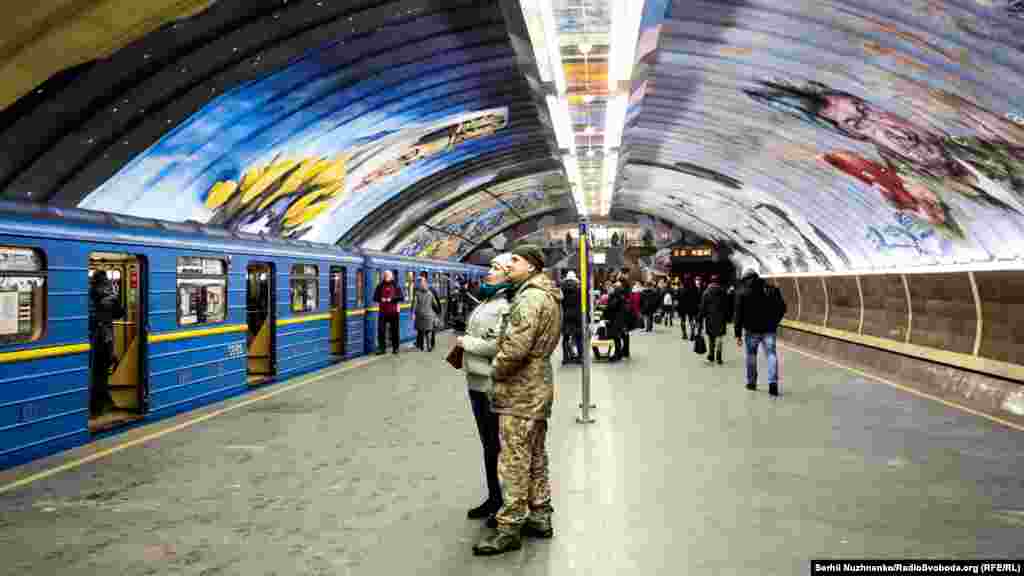 Військовий із дружиною розглядають один з муралів на станції метро &laquo;Осокорки&raquo;